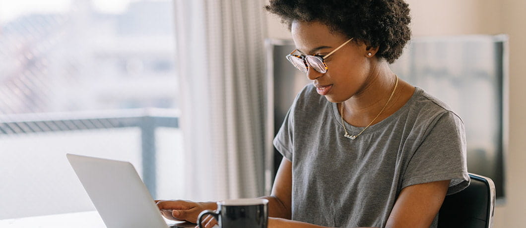 Stock image of a woman working at a laptop with a cup of coffee