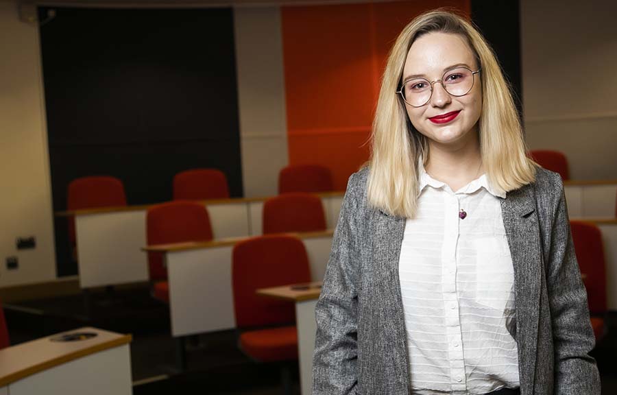 A student in business wear standing in front of empty lecture theatre seating