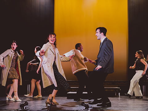 Several students singing and dancing on stage