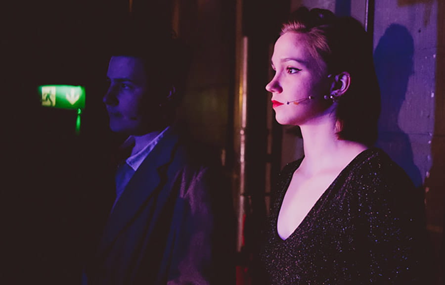 Two students waiting for their cue in a darkened theatre