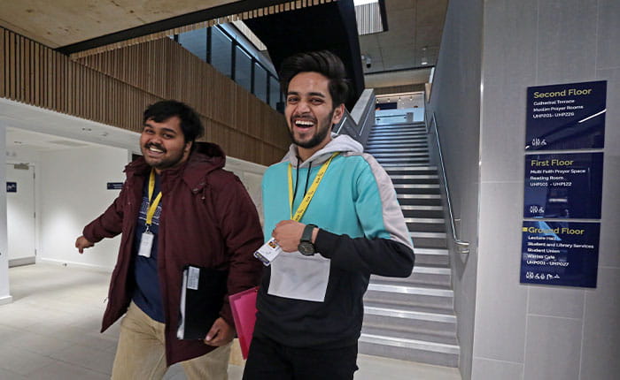 Two students walking down a corridor in University House