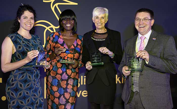 Four winners of the 2022 Alumni Awards holding their trophies