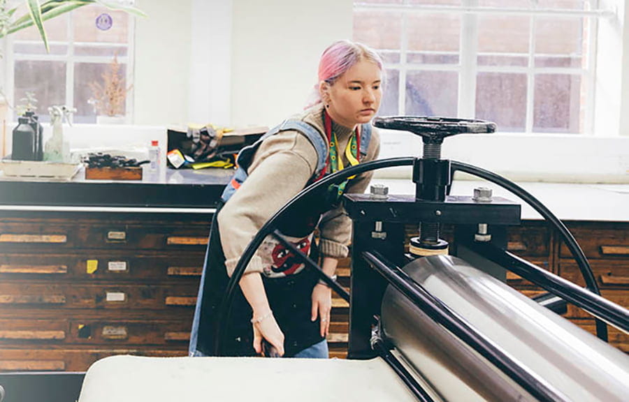 A student using a printing press in an art studio