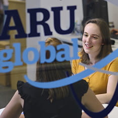 Two young women talking in the ARU Global office