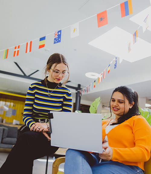 Two international students looking at a laptop