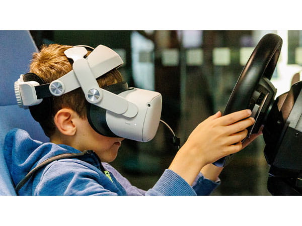 A child wearing a VR headset holding a steering wheel