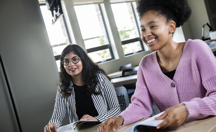 Two students looking to the front of a classroom, smiling