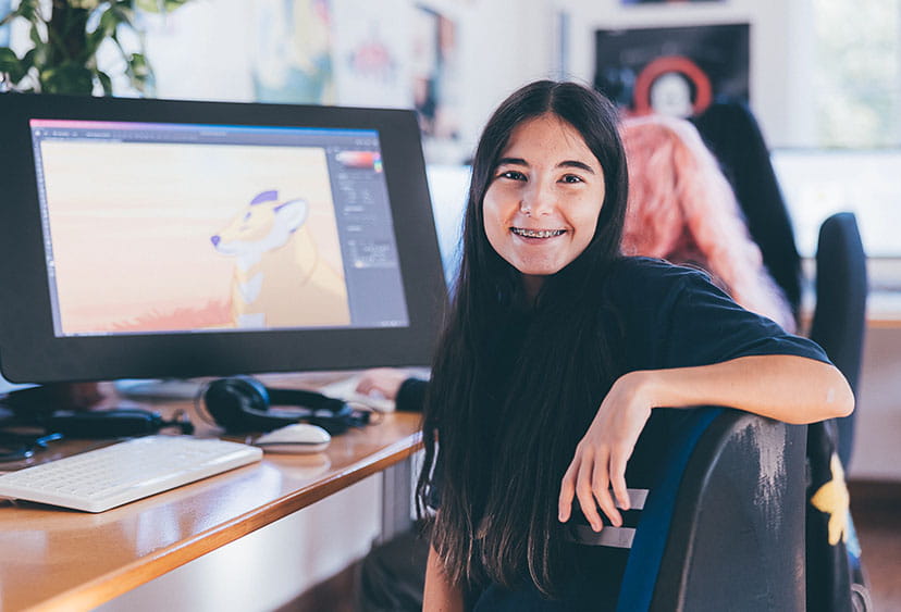 Design student sitting at a desk with two computer screens on it
