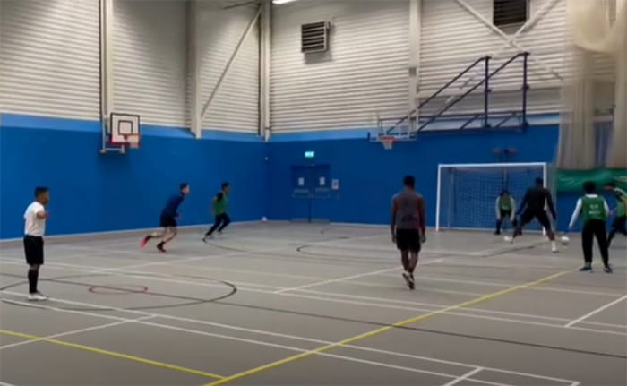 Students playing football in a sports hall