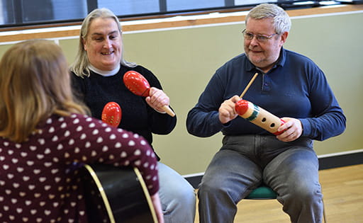Three older people and a carer playing instruments in a music therapy session