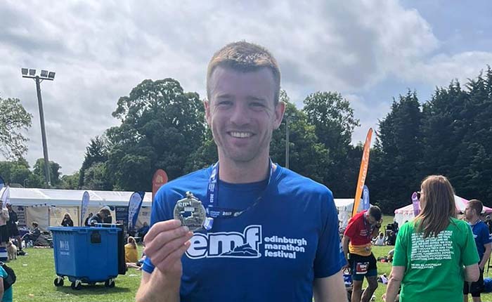 ARU staff member with medal after completing a marathon