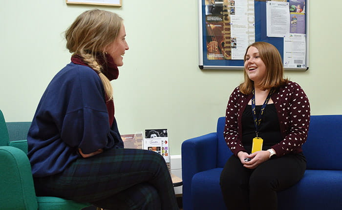 Two people sitting on sofas, talking and laughing