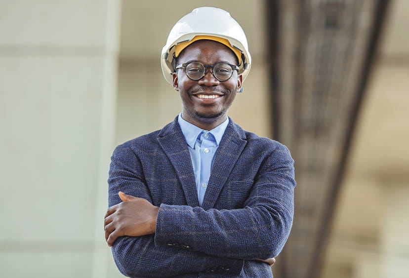 A smiling civil engineer in a suit and hard hat