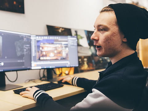 A student working at two computer monitors