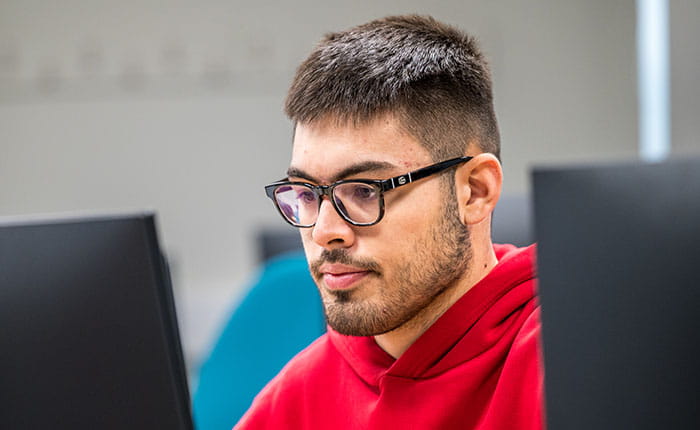 A student looking at a computer screen, with a second screen slightly visible on the right