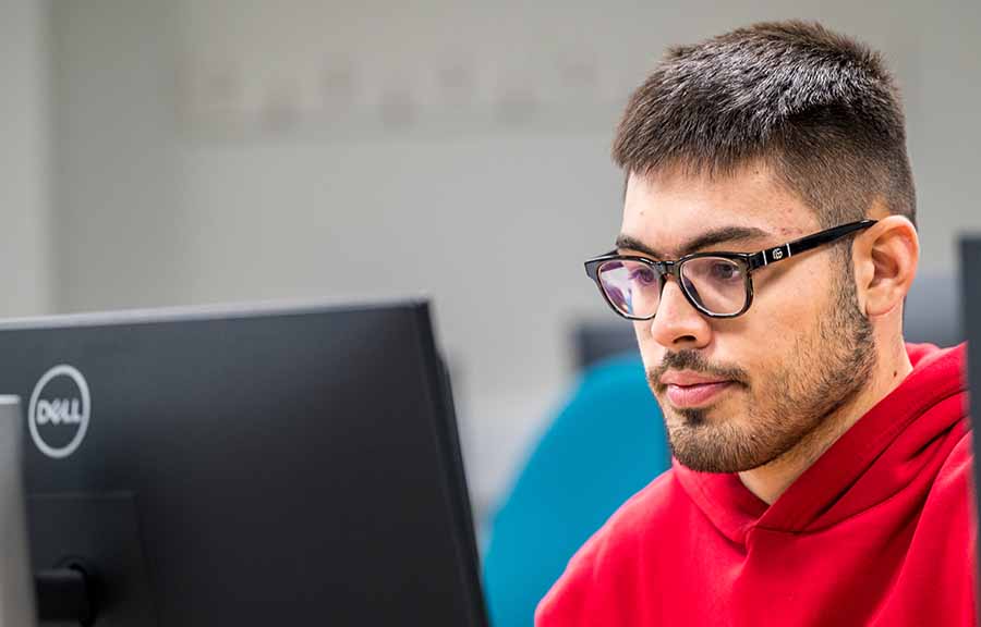 A student looking at a computer screen, with a second screen slightly visible on the right