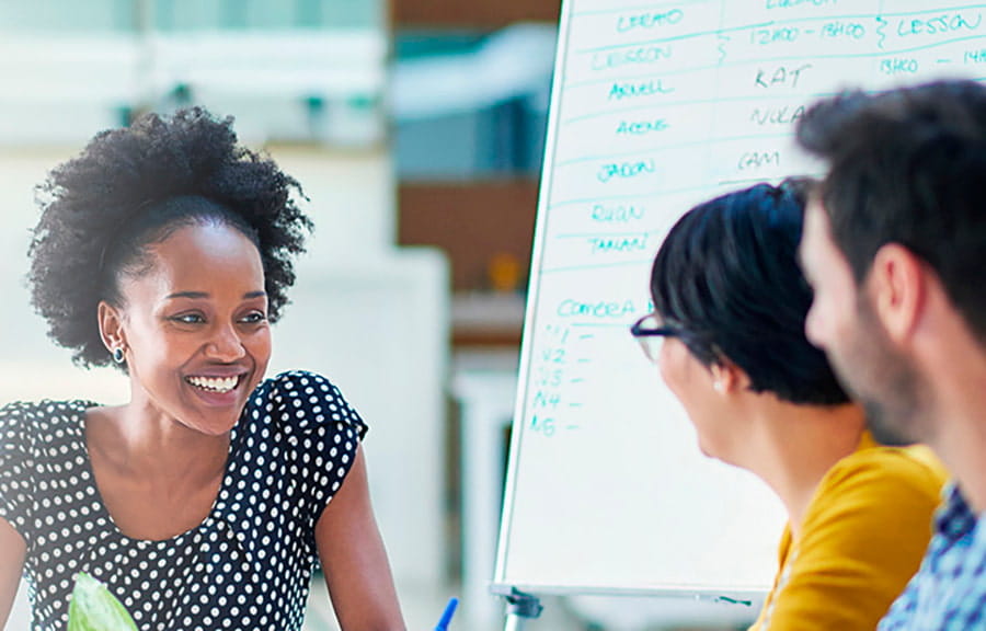 Three people discussing ideas in front of a whiteboard