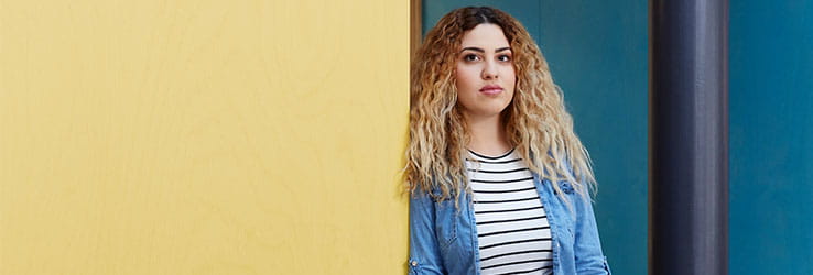 A student leaning on a yellow wall