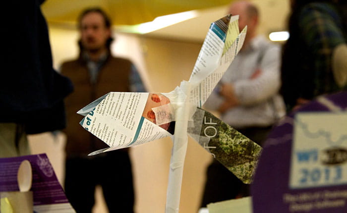 Paper model of a wind turbine, with small group of students seen in background