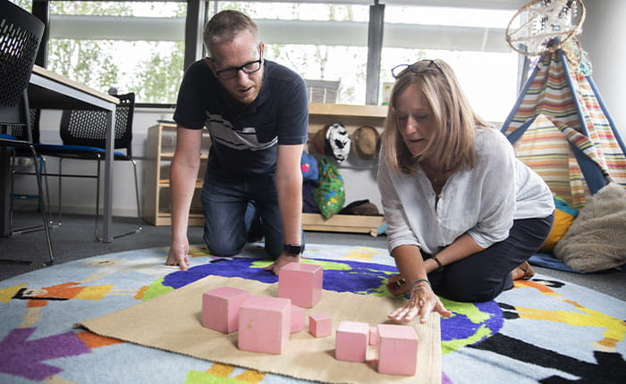 Adults stacking pink building blocks