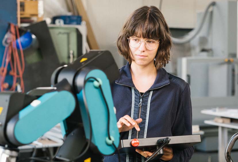 An Electro-mechanical Engineer uses a computer to work a robotic arm