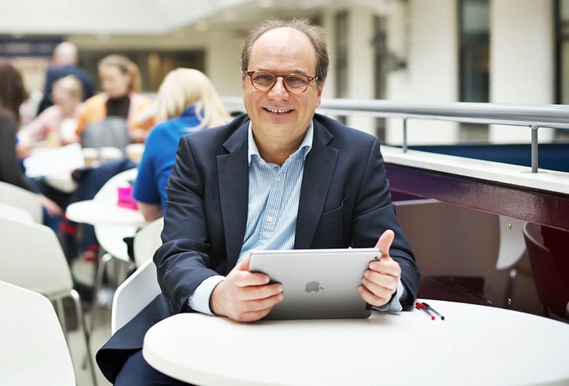 Emanuele Giovannetti holding an iPad while sitting at a small round table