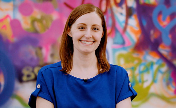 Emma, Director of Big Bear Creative, in front of a colourful graffiti wall