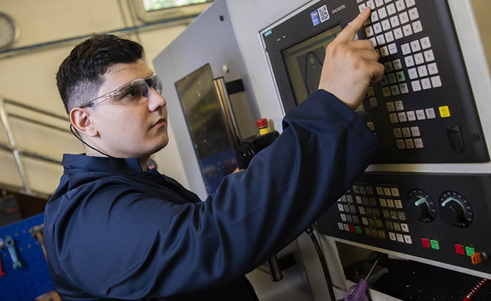 A student pressing buttons on a machine in the engineering lab
