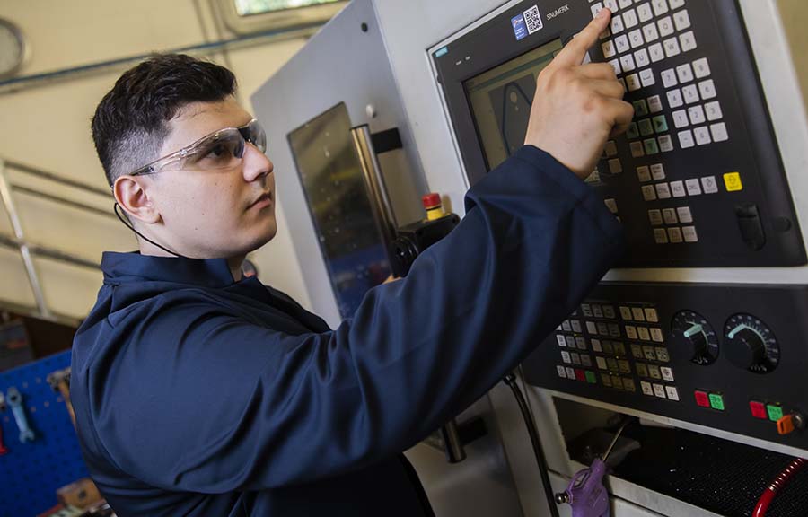 A student pressing buttons on a machine in the engineering lab
