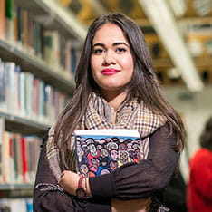 Student holding books in library