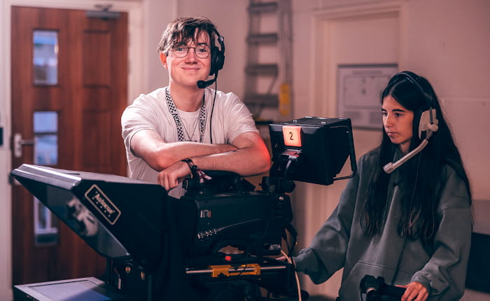 Two students operating film equipment
