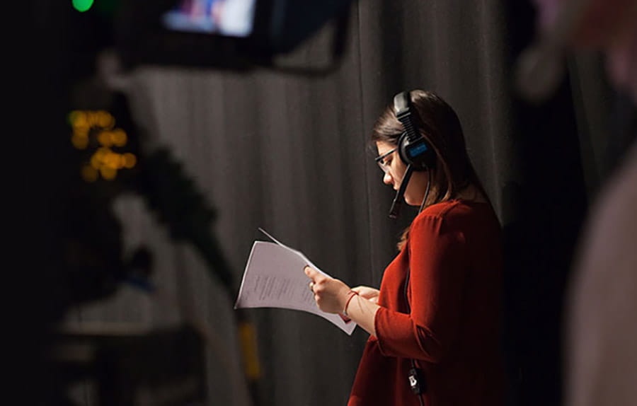 Student wearing headphones and looking at a script in a film and TV studio