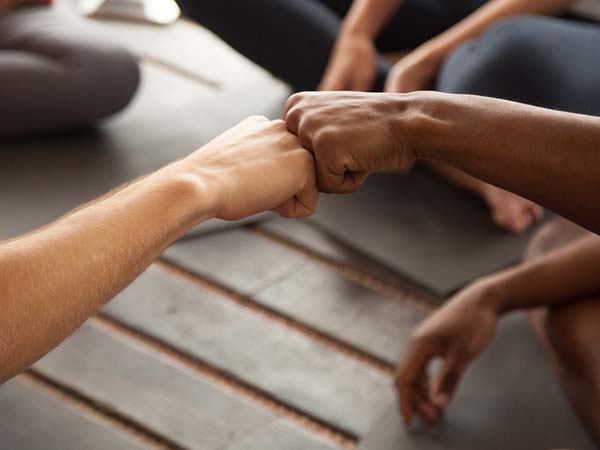 Close-up of two people fist-bumping while sitting in a small group