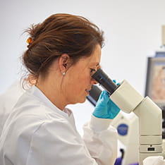 Female healthcare professional looking through microscope