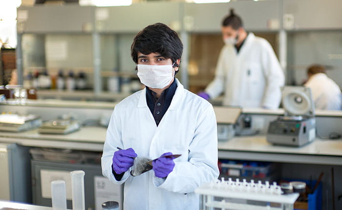 People in lab coats and gloves working in a forensic lab