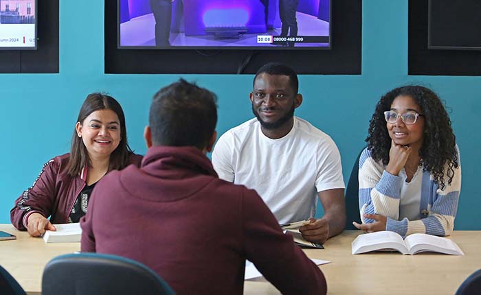 Four students sat around a table, three facing one