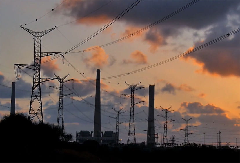 Video still of electricity pylons and factory chimneys at dusk