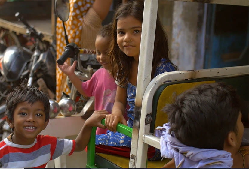 Four children in and next to the back of a rickshaw in India