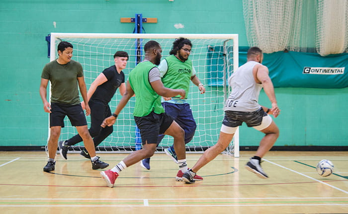 Group of people playing football in a sports hall