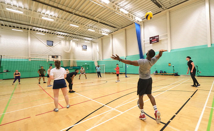 Group of people playing volleyball in a sports hall