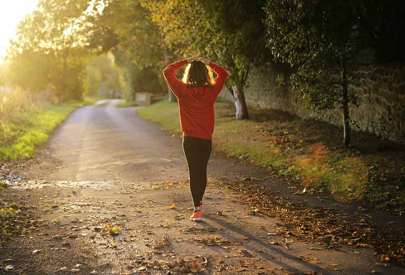 A woman in activewear walking down a woodland path