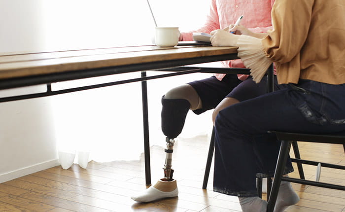 Man with prosthetic leg sitting at a desk with a woman