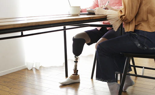 Man with prosthetic leg sitting at a desk with a woman