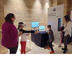 Two children using VR equipment in an exhibition space, as two adults look on