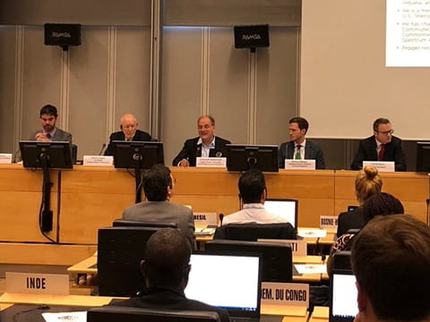 Emanuele Giovannetti speaking at the ITU, with two people either side of him on the panel and the backs of five audience members 