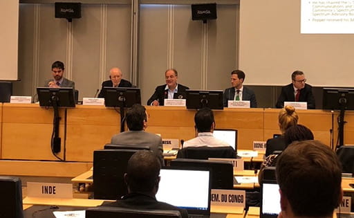 Emanuele Giovannetti speaking at the ITU, with a person either side of him on the panel and the backs of three audience members 