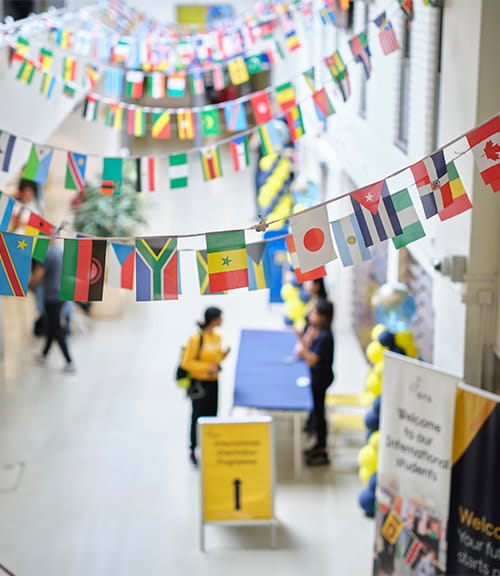 International flags fly over the concourse in Cambridge campus