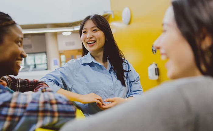 Three international students discussing and laughing