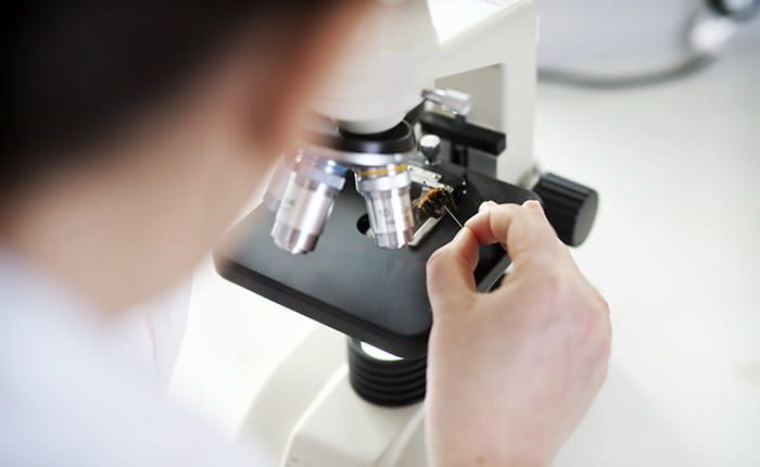 A woman looking down a microscope