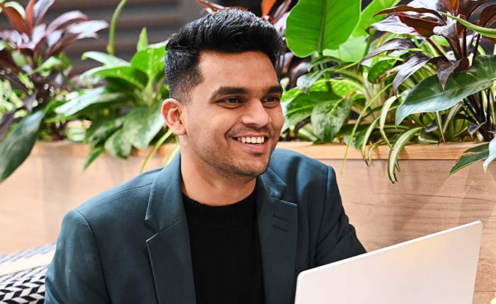 A student using a laptop, with greenery adorning a ledge in the background